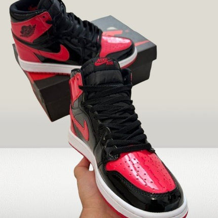 Close-up of Jordan 1 Patent-Bred's glossy red patent leather toe box and perforated detailing