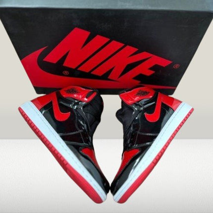 Jordan 1 Patent-Bred shoes under lighting highlighting glossy red accents and black stitching